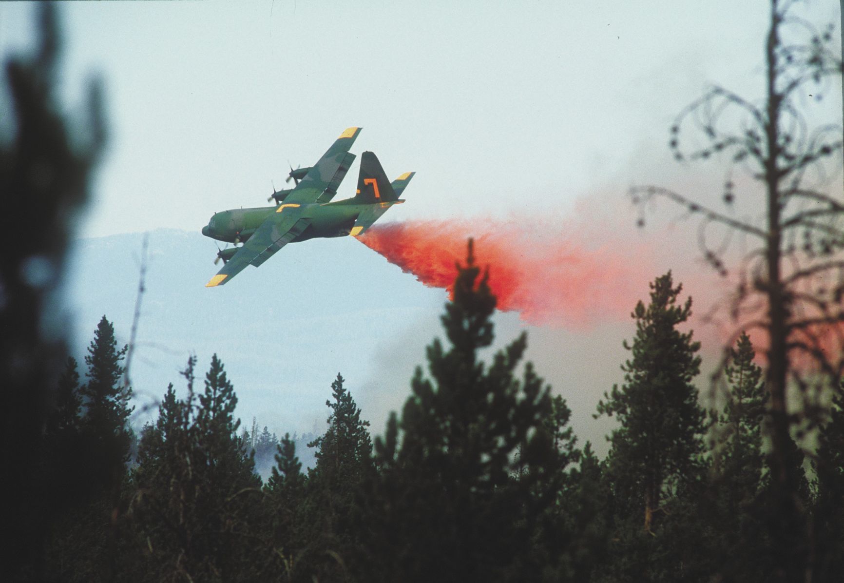 A C-130 drops retardant